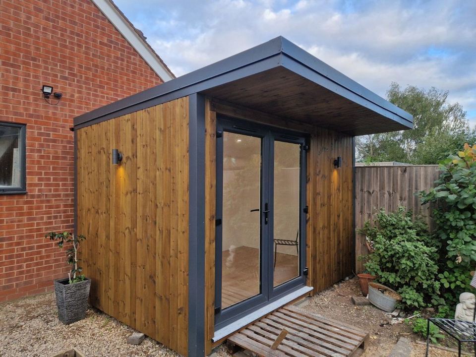 Stained pine and near-black steel garden room by day